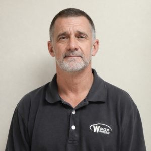 Portrait of a man wearing a Wade Heating & Air black polo shirt against a neutral background